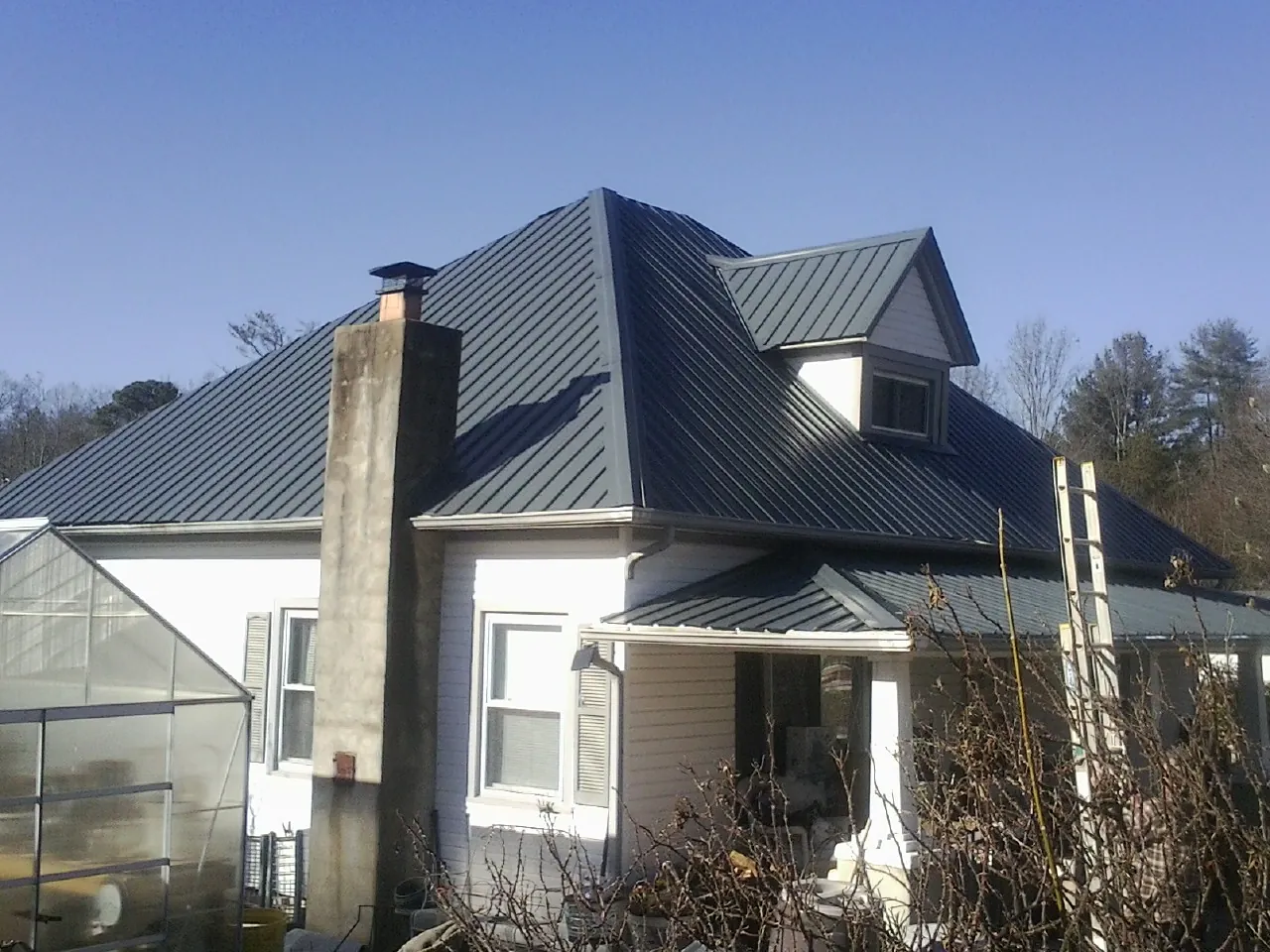 Dark blue standing seam metal roof on a white farmhouse with dormer — Slate & Tile Roof Repair by Roofing Brothers in Felicity