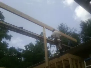 Carpenter setting a ridge beam over a new addition frame — Ice Dam Removal by Roofing Brothers in Felicity