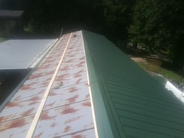 Old rusted panels beside newly installed green metal roofing — Wind Damage Roof Repair by Roofing Brothers in Felicity