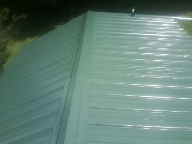 New green metal panels meeting at the ridge of a roof — Flat Roof Repair work by our crew in Felicity