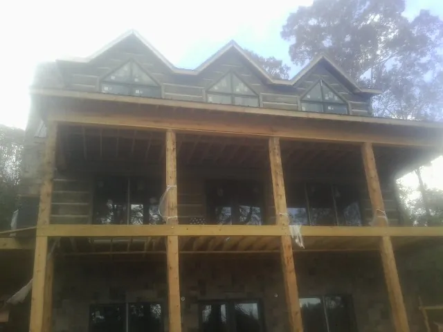 Dormers and porch framing on a large log home under construction — Roof Coating work by our crew in Felicity