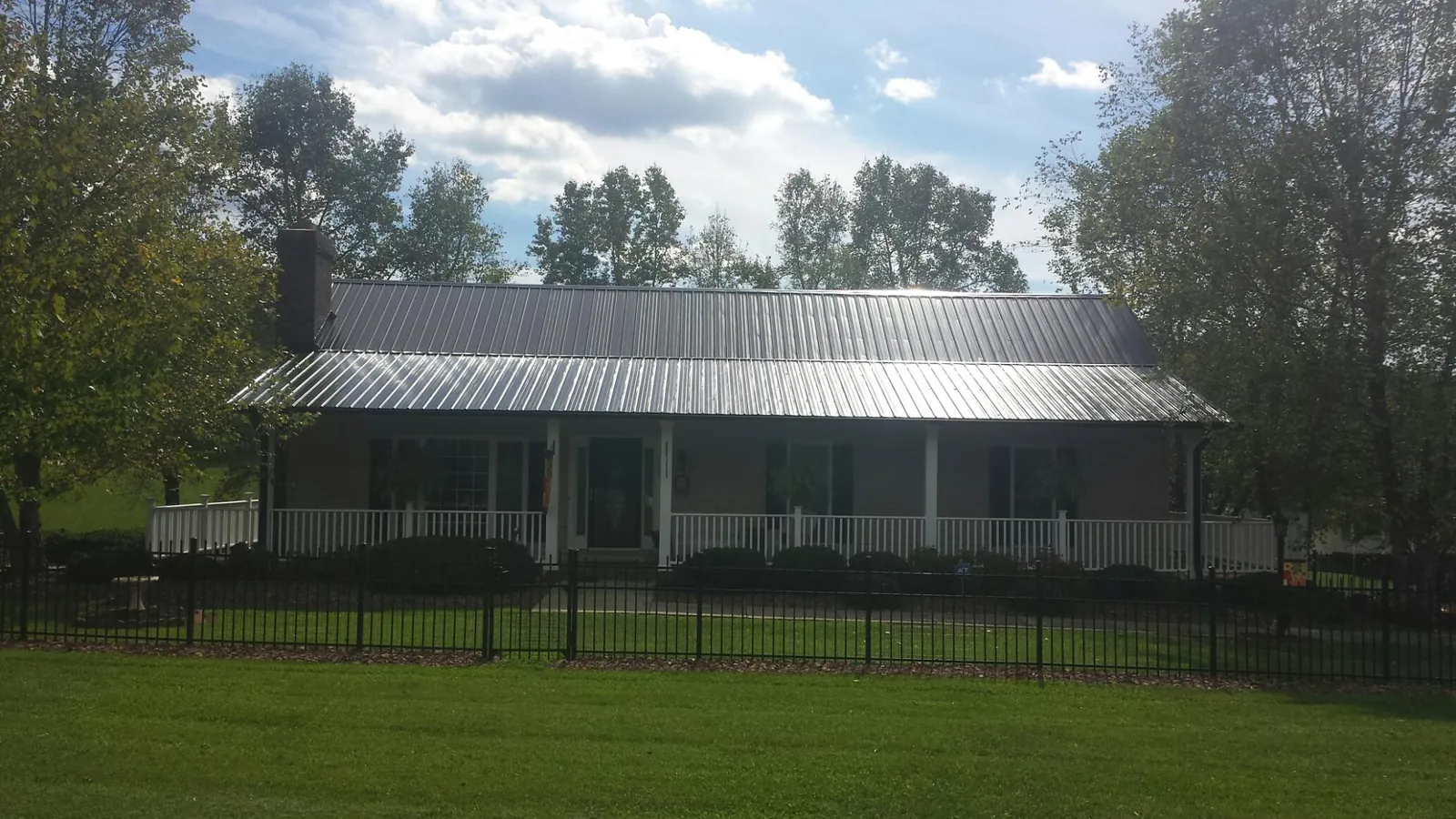 Gray metal roof on a brick ranch with a full width front porch — Gutter Guard Installation work by our crew in Felicity