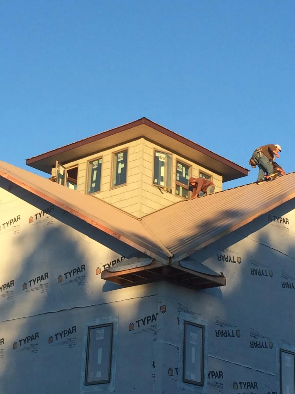 Roofers working around a rooftop cupola on a new metal roof at sunset — Roof Waterproofing in Felicity by Roofing Brothers